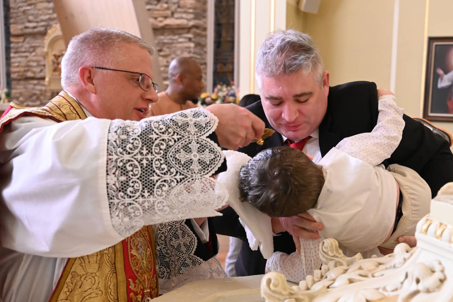 A priest is feeding the bride 's cake.